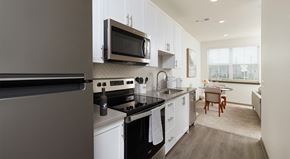 Championsgate apartment for rent - A modern kitchen with a refrigerator, microwave, oven, and a dining area with a table and chairs.