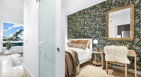 Seattle apartment for rent - A bedroom with a floral wallpaper and a large mirror above the bed.