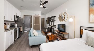 Championsgate apartment for rent - A modern kitchen and living room with a blue chair and a white bed.