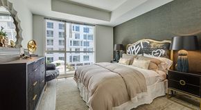 Los Angeles apartment for rent - A bedroom with a large bed, a dresser, and a window overlooking a building.