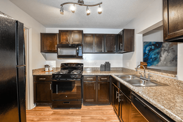 Douglasville apartment for rent - A kitchen with a black refrigerator and brown cabinets.