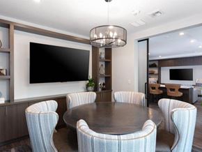 Santa Clara apartment for rent - Apartments for Rent in Santa Clara, CA - Santana Terrace - A Dining Area with a Round Table, Upholstered Chairs, and a Large Wall-Mounted TV.
