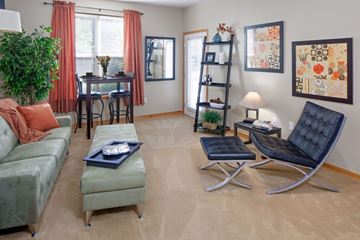 Portland apartment for rent - A living room with a green couch, a black chair, and a table with a vase on it.