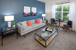 Portland apartment for rent - A living room with a grey couch, a glass coffee table, and two chairs.