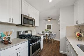 Downey apartment for rent - A kitchen with white cabinets and a black stove top.