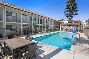 Downey apartment for rent - A pool with a table and chairs in front of a building.