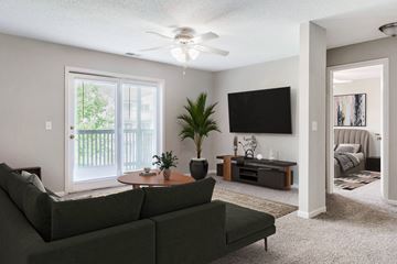 Springfield apartment for rent - A living room with a green couch and a flat screen TV mounted on the wall.