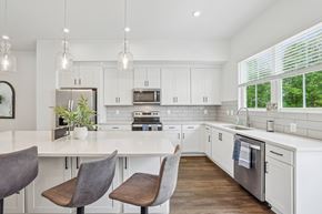 Avondale Estates townhouse for rent - Kitchen with white cabinets and a large island with chairs at Henley Avondale in Avondale Estates, GA.