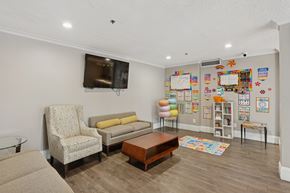 Lawrenceville townhouse for rent - A living room with a chair, a sofa, a coffee table, and a wall with a TV and a bookshelf.