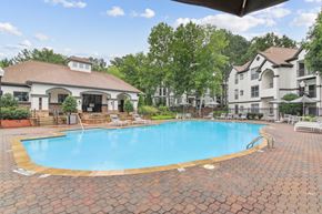 Duluth apartment for rent - A large outdoor swimming pool surrounded by a brick patio and lounge chairs.