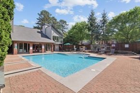 Lawrenceville townhouse for rent - A large swimming pool surrounded by a brick patio and a building in the background.