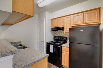 Houston apartment for rent - A kitchen with black appliances and wooden cabinets.