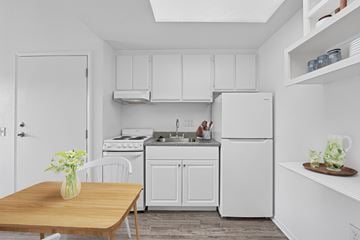 San Dimas apartment for rent - A kitchen with white appliances and a wooden table with a vase of flowers on it.