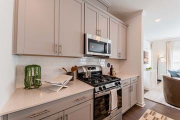 Raleigh townhouse for rent - A modern kitchen with a stove top oven and microwave above it.