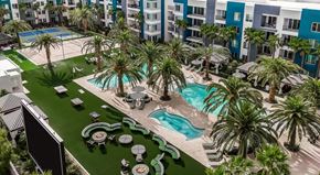 Henderson apartment for rent - A large swimming pool surrounded by palm trees and lounge chairs.