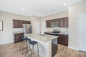 Dade City townhouse for rent - A kitchen with a white island and dark brown cabinets.