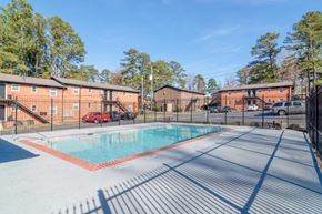 Atlanta apartment for rent - A swimming pool surrounded by a fence with a building in the background.