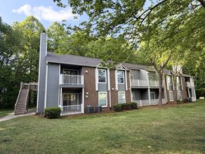 Greensboro apartment for rent - Apartment building with a grey and brown exterior and a tree in front.