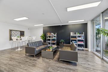 Wilton Manors apartment for rent - A modern living room with grey sofas and a black bookshelf.