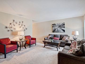 Greenville apartment for rent - A living room with a grey carpet and a large painting on the wall.