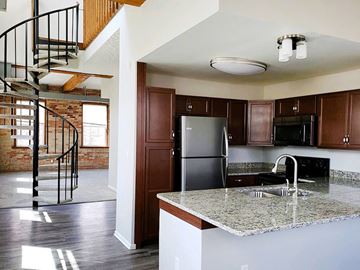 Grand Ledge townhouse for rent - a kitchen with a marble counter top and a spiral staircase