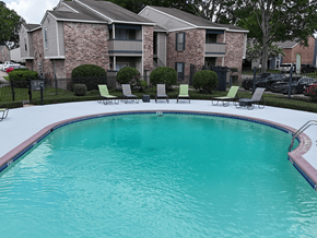 Baton Rouge apartment for rent - A swimming pool in front of a brick apartment building.
