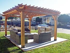Evansville apartment for rent - a patio with a seating area and a wooden pergola with grill station
