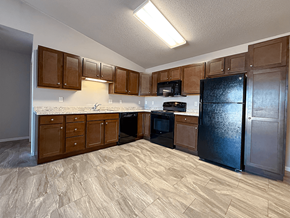 Williston apartment for rent - A kitchen with wooden cabinets and a black refrigerator.