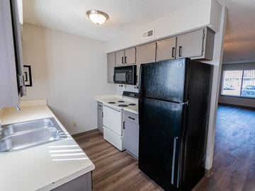 Wichita townhouse for rent - A black refrigerator stands in a kitchen with a stainless steel sink.
