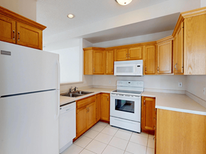 Rochester townhouse for rent - A kitchen with wooden cabinets and white appliances.