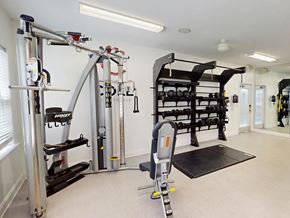 Fayetteville apartment for rent - A home gym with a variety of equipment including a squat rack, bench, and weightlifting machines.