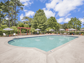 Fayetteville apartment for rent - A large outdoor swimming pool surrounded by trees and lounge chairs.