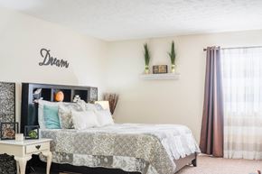 Omaha apartment for rent - A bedroom with a bed, a nightstand, and a wall decoration that says