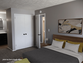 Omaha apartment for rent - A bedroom with a bed, nightstand, and two doors.