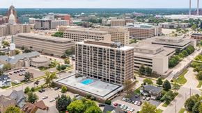 Lansing apartment for rent - A large building with a pool in the middle of a parking lot.