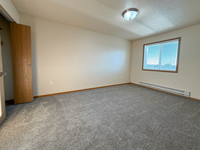 Williston apartment for rent - A room with a carpeted floor, a window with blinds, and a door.