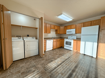 Williston apartment for rent - A kitchen with white appliances and wooden cabinets.