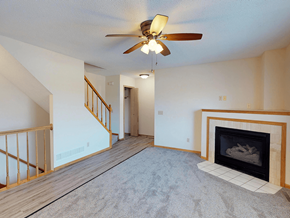 Rochester townhouse for rent - A living room with a fireplace and a ceiling fan.