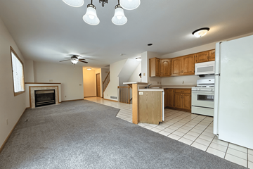 Rochester townhouse for rent - A spacious kitchen and living room with a fireplace and a ceiling fan.