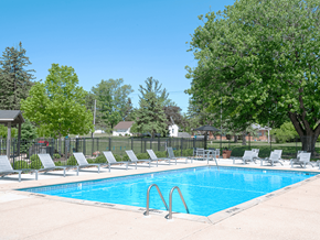 Grand Rapids apartment for rent - a swimming pool with chaise lounge chairs and trees in the background