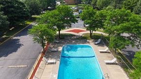 Brooklyn Park apartment for rent - A swimming pool surrounded by trees and a parking lot.