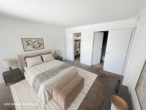 Rochester townhouse for rent - A bedroom with a large bed and a wardrobe in the background.