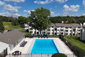 Omaha apartment for rent - A swimming pool surrounded by a fence and chairs with apartment buildings in the background.