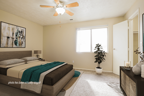 Omaha apartment for rent - A bedroom with a bed, a ceiling fan, and a plant.