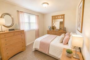 Rantoul townhouse for rent - A bedroom with a bed, dresser, mirror, and lamp.