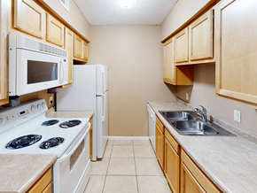 Wichita apartment for rent - A kitchen with a white stove top oven and a white refrigerator.