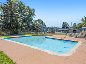 Okemos apartment for rent - A large outdoor swimming pool surrounded by trees and lounge chairs.