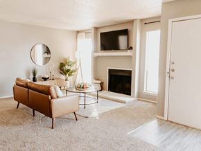 Lubbock apartment for rent - A living room with a brown sofa, a fireplace, and a mirror on the wall.