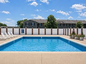 South Bend apartment for rent - A swimming pool surrounded by a white fence and chairs.