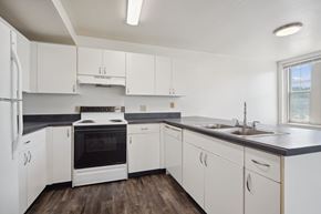 Moline apartment for rent - A kitchen with white cabinets and a black countertop.